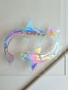 two colorful fish stickers sitting on top of a white wall