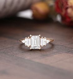 an emerald cut diamond ring on a wooden table