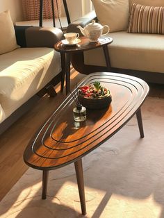 a wooden table sitting in the middle of a living room next to a white couch