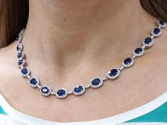 This tennis necklace features 17.50 ct of blue sapphires surrounded by 4.30 ct of round diamonds, G/H-VS/SI quality, set in 14K white gold. Luxury Sapphire Necklace With Halo Setting, Sapphire Tennis Necklace, Design Catalog, Blue Sapphire Necklace, Diamond Tennis Necklace, Tennis Necklace, Neck Chain, Wedding Jewellery Necklace, Necklace Blue