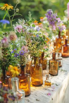 a table topped with lots of vases filled with different types of wildflowers