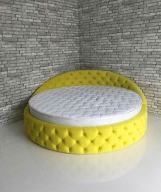 a yellow round bed sitting on top of a white floor next to a brick wall