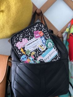 a black purse with some stickers on it and a yellow chair in the background