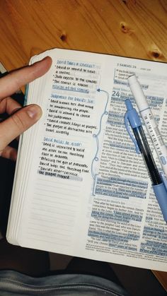 a person holding a pen over an open bible