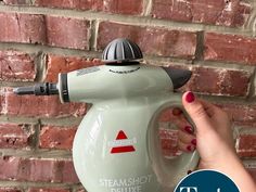 a woman is holding a steam kettle in front of a brick wall with the words steam shot deluxe written on it