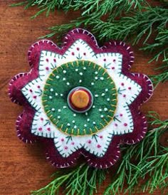 an ornament made out of fabric on top of a wooden table next to pine branches