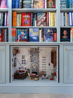 a bookshelf filled with lots of books next to a fireplace