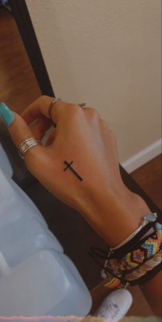 a woman's hand with a cross tattoo on it