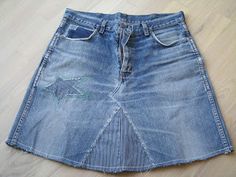 a blue jean skirt with an elephant embroidered on the front and side, sitting on a wooden floor