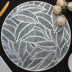 a white plate sitting on top of a table next to some flowers and plates with utensils