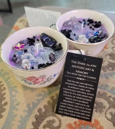 two cups filled with ice sitting on top of a table next to a sign that says the dark moon apothecation & laboratory