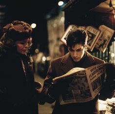 a man and woman looking at a newspaper