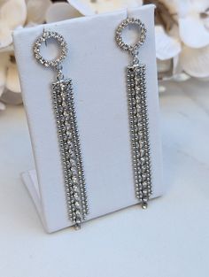 These eye-catching crystal rhinestone earrings will make you look and feel special. They feature a beautiful circular rhinestone post with one rhinestone fringe strand and four strands of silver ball chain that add glamour and glitz.  The earrings elegantly hang from silver-plated stainless steel ear wires. For those who prefer gold-filled wires, we offer them for an additional $6.00 fee. Your comfort and satisfaction are our priorities, so please feel free to message us about this customization. Length - 3 inches  Width - .5 inches Elegant Metal Earrings With Rhinestone Fringe, Crystal Linear Earrings For Party, Glamorous Cubic Zirconia Linear Earrings For Parties, Wedding Chandelier Earrings With Rhinestone Fringe, Party Dangle Crystal Earrings With Rhinestone Fringe, Glamorous Silver Linear Metal Earrings, Glamorous Crystal Linear Earrings For Party, Glamorous Crystal Linear Earrings For Evening, Silver Dangle Jewelry With Rhinestone Fringe