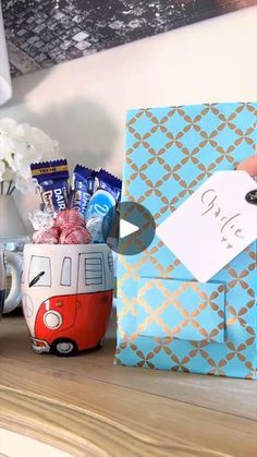 a coffee cup with candy and candies in it sitting on a table next to a blue box