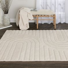 a white rug on the floor in front of a window with curtains and a bench