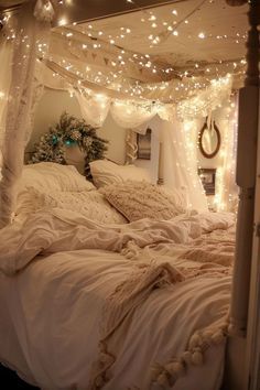 a bed with white sheets and lights on the headboard is in a room that has been decorated for christmas