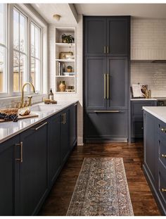 a kitchen with dark blue cabinets and white counter tops, gold pulls on the handles