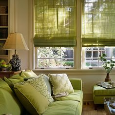 a living room with green couches and pillows