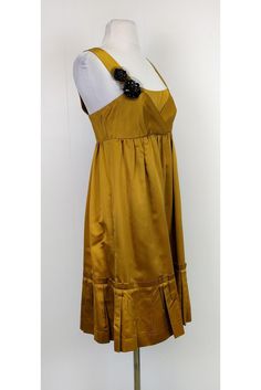 With its gorgeous gold tone color and feminine empire waist silhouette, this dress is a polished choice. Perfect for any party, style it with gold-tone jewelry and chic pumps. Size 6 60% silk, 40% rayon Back zipper closure Beaded detail on strap Empire waist silhouette Ruffles along hem Lined Bust 31" Waist 28.5" Shoulder to hem 38.25" Gold Satin Dress With Fitted Bodice, Gold A-line Silk Dress, Gold Cocktail Dress With Fitted Bodice, Elegant Gold A-line Dress, Gold Dressy Summer Dress, Dressy Gold Summer Dress, Gold Satin Cocktail Dress, Gold Formal Dress For Spring, Chic Gold Formal Dress