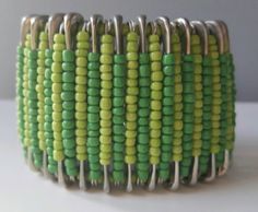 a green and yellow beaded bracelet with metal clasps on a white table top