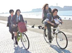 three people riding bicycles on the beach