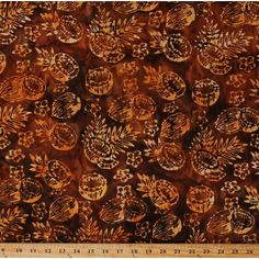 an orange and brown fabric with leaves on the side, in front of a ruler