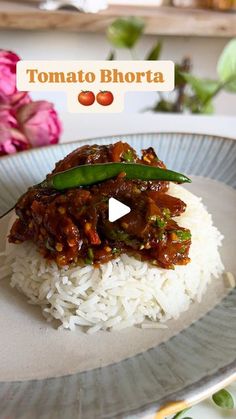 a plate topped with rice and meat covered in gravy next to pink flowers