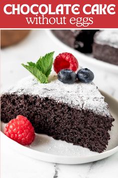 a slice of chocolate cake on a plate with raspberries and blueberries next to it