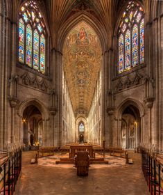 the inside of a large cathedral with stained glass windows and pews in front of it