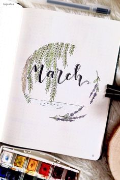 an open notebook with the word march written in cursive writing and watercolors