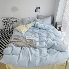 an unmade bed in a white room with black and white checkered flooring