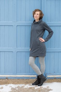 a woman standing in front of a blue garage door with her hands on her hips