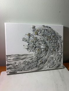 a painting is shown on top of a piece of white paper with silver glitters