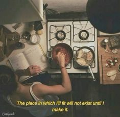 a woman reading a book in front of an oven with food on the stove top