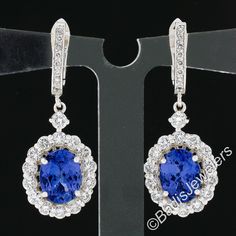 "These gorgeous, custom designed, earrings are newly crafted from solid 14k white gold and feature a drop dangle style that carries a stunning tanzanite with fine quality, round brilliant cut, diamonds throughout. The top of the earrings are neatly lined with diamonds and are followed by larger diamonds that gently dangle below, with one individually set and the remaining set throughout the elegant halo design. The tanzanite stones show the most incredible, eye-catching, violetish-blue color tha Formal Gia Certified Oval Earrings, Oval Sterling Silver Earrings, Tanzanite Stone, Halo Design, Drop Dangle Earrings, Diamond Drops, Brilliant Diamond, How To Make Earrings, Round Brilliant