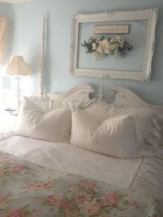 a white bed sitting in a bedroom next to a window with flowers on the headboard