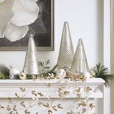 three silver cones are sitting on top of a mantel