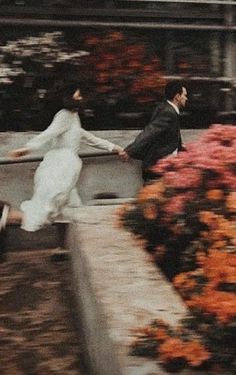 a man and woman are walking down the street with flowers in front of their backs