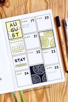 an open planner sitting on top of a wooden table next to a pen and pencil