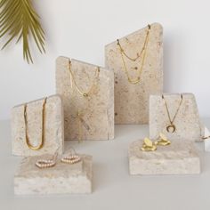 four pieces of jewelry sitting on top of a white counter next to a palm tree