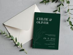 a wedding card and envelope with greenery