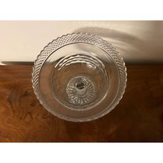 a clear glass bowl sitting on top of a wooden table next to a white wall