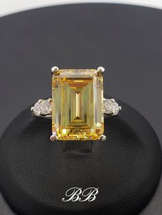 Made to order.  Please allow up to 3 weeks for production. This listing is for a 925 unplated sterling silver ring with a high quality canary yellow emerald cut cubic zirconia diamond and your choose of ring setting. Center Stone Gem Type:  Lab Created Cubic Zirconia Diamond Shape: Emerald Cut Size: 14x10mm Weight: 8.5 carats approximately Color: Canary Yellow Quality: 5A Hardness: 8.5 Mohs Accent Stones Gem Type:  Lab Created Cubic Zirconia Diamond Shape: Round Brilliant Size: (4) 3mm Color: White Quality: 6A Hardness: 8.5 Mohs Ring Setting Options Multi-Stone (As shown in photos) Three Stone Ring (example - www.etsy.com/listing/1280862056) Solitaire Ring (example - www.etsy.com/listing/1264625901) Did you know there are different grades of cubic zirconia? (A - 6A) The higher the grade, t Canary Yellow Diamond Ring Emerald Cut, Yellow Diamond Engagement Ring Emerald, Luxury Yellow Gold Emerald Cut Gemstones, Yellow Emerald Cut Engagement Ring, Yellow Emerald Engagement Ring, Yellow Platinum Fine Jewelry, Cubic Zirconia Gemstones With Prong Setting For Anniversary, Yellow Diamond Emerald Cut Ring, Anniversary Cubic Zirconia Gemstones With Prong Setting