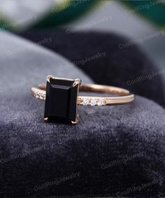 an engagement ring with a black stone surrounded by white diamonds on a velvet cushioned surface