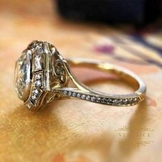 an antique style engagement ring is shown on a gold tablecloth with other items in the background