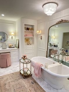 a white bath tub sitting in a bathroom next to a mirror and vanity with lights