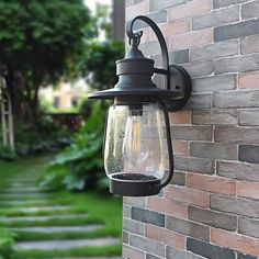 a light that is on the side of a brick wall next to a garden path