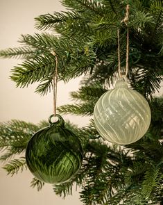 two glass ornaments hanging from a christmas tree