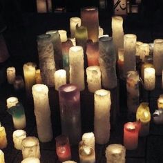 many lit candles are arranged in rows on the ground