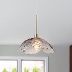 a light fixture hanging from the ceiling in a room with large windows and wooden cabinets